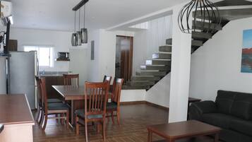 A modern living space with a dining area, kitchen, and staircase.