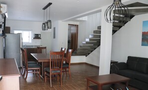 Un espacio habitable moderno con comedor, cocina y escalera.