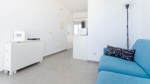 A modern living room with a blue sofa, a white console table, and a floor lamp. - YourHouse Monges sea view-studio (Can Picafort)