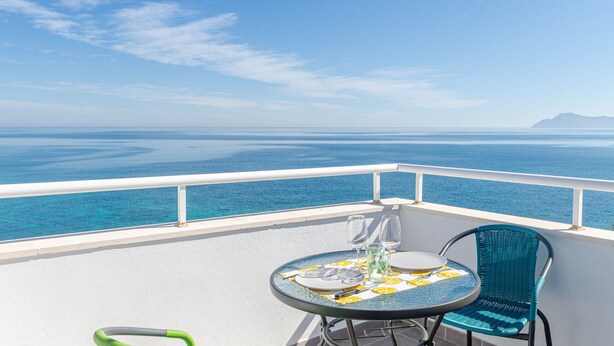 A balcony with a table set for two, overlooking a vast ocean. - YourHouse Monges sea view-studio (Can Picafort)