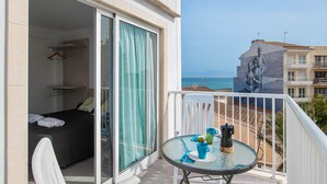 Un balcón con mesa, sillas y vista al mar.