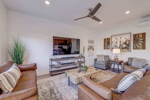 A modern living room with leather sofas, a coffee table, a TV, and artwork on the walls.