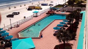 A beach view with a swimming pool, umbrellas, and beach chairs. - DAYTONA GETAWAY OCEAN FRONT CONDO (Daytona Beach)