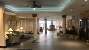 A spacious lobby with a high ceiling, a central fountain, and a seating area with wicker furniture. - DAYTONA GETAWAY OCEAN FRONT CONDO (Daytona Beach)