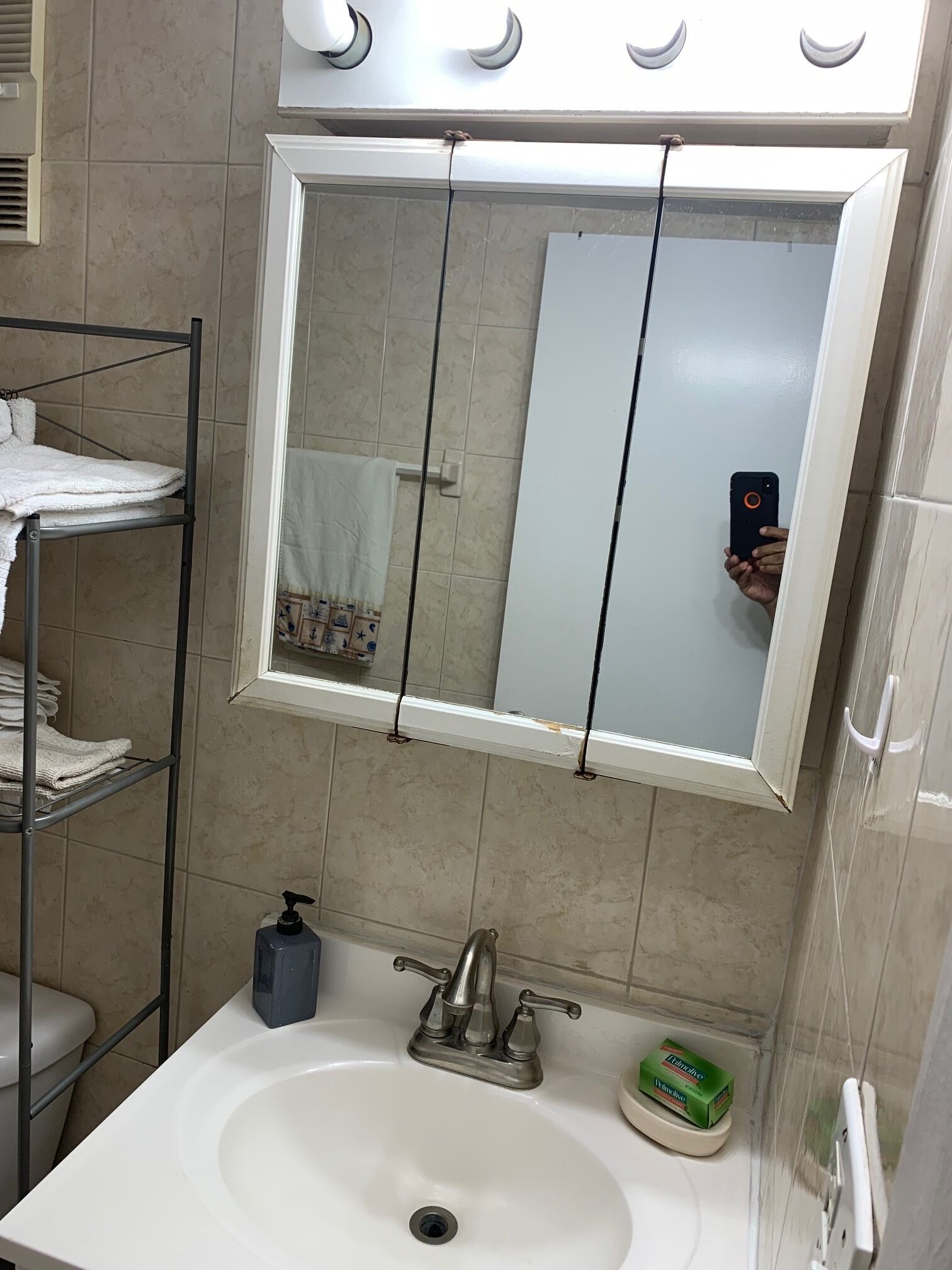 Une salle de bain avec un lavabo blanc, un miroir, un porte-serviettes et un distributeur de savon.