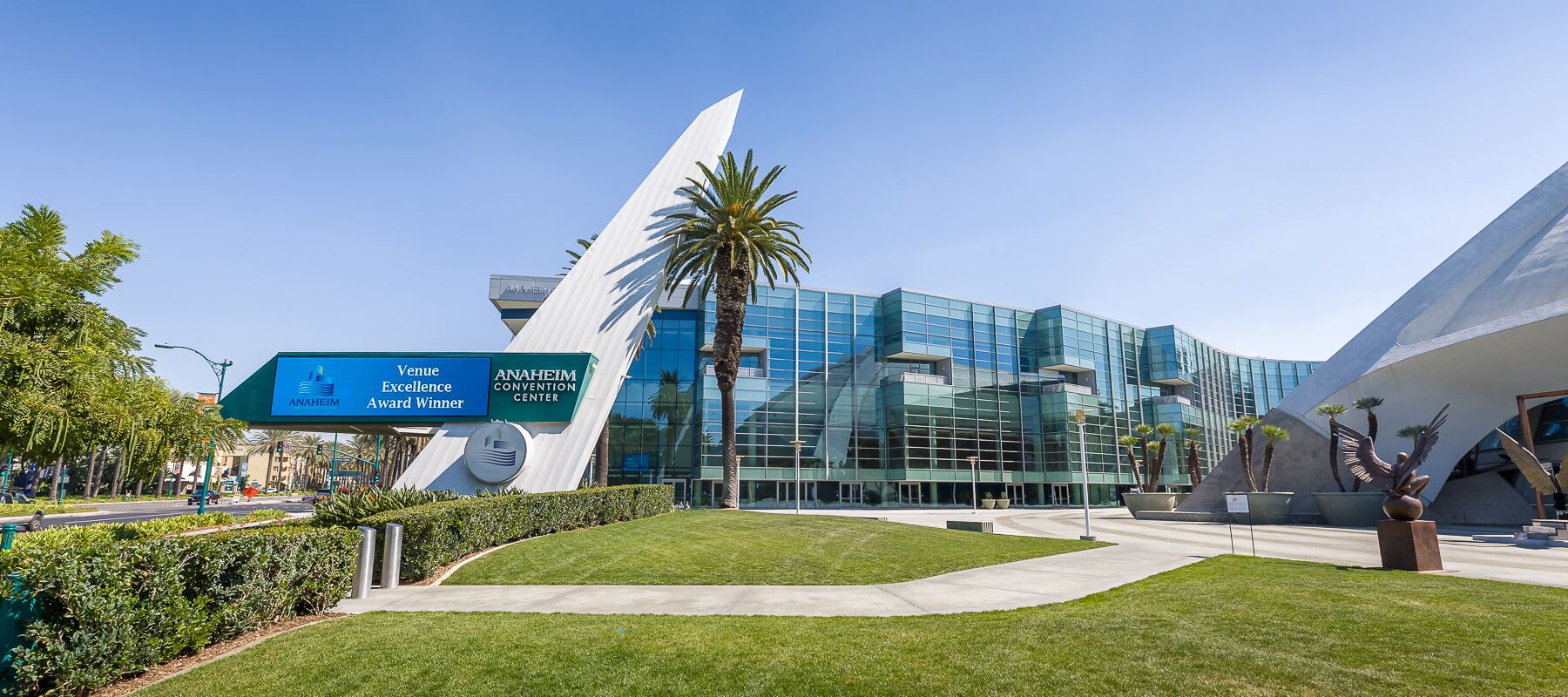 Moderni rakennus, jossa on lasijulkisivu, huomiota herättävä valkoinen veistos ja kyltti, joka kertoo sen olevan Anaheimin kongressikeskuksen (ANAHEIM CONVENTION CENTER) tapahtumapaikka.