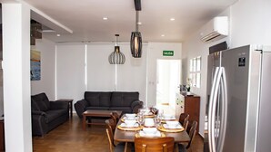 A modern living room with a sofa, dining table set for four, and a refrigerator. - Topacio 2 Joyas del mar San Carlos (San Carlos)
