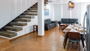 A modern living space with a wooden staircase, a dining area set for six, and a gray sofa. - Topacio 2 Joyas del mar San Carlos (San Carlos)