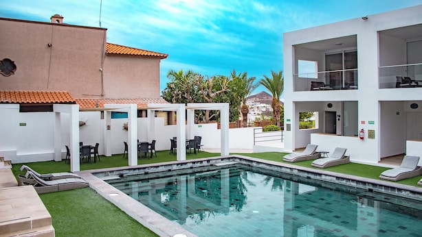 A pool area with lounge chairs, a small pool, and a building with a tiled roof. - Topacio 2 Joyas del mar San Carlos (San Carlos)