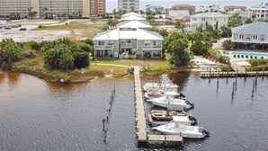 A waterfront hotel with a dock, boats, and a large building in the background. - Live the Salt Life in Golden Dog's Destin Rental (Destin)
