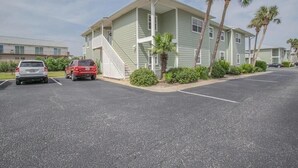 A two-story motel with a covered front porch, a parking lot, and palm trees. - Live the Salt Life in Golden Dog's Destin Rental (Destin)