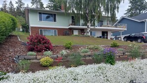 Ein zweistöckiges Haus mit Vorgarten, der ein Blumenbeet und eine Steinschüttung zeigt.