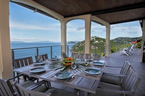 Une table à manger dressée pour six personnes, avec vue sur la mer et les collines.