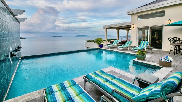 Ein Poolbereich mit Liegestühlen und Blick aufs Meer.