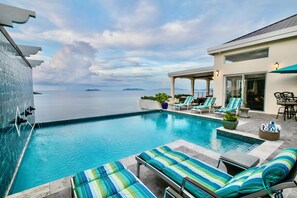Un espace piscine avec des chaises longues et vue sur la mer.
