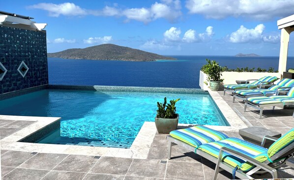 Un espace piscine avec des chaises longues et vue sur la mer.