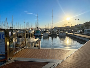 A marina with boats docked, a wooden deck, and a clear sky.
