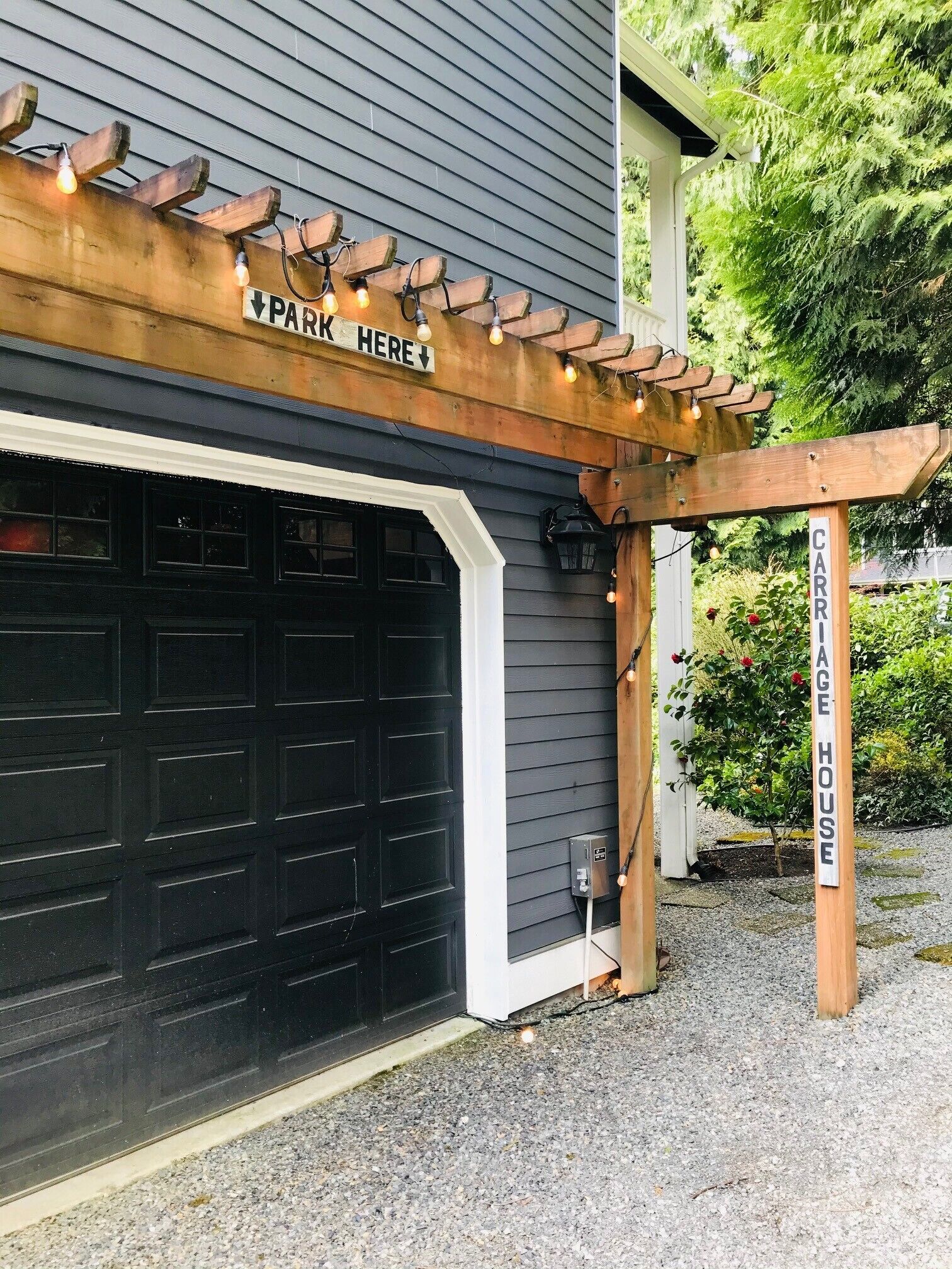 A garage with a wooden pergola above it, labeled "PARK HERE" and "CARRIAGE HOUSE".