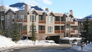 Ein mehrstöckiges Hotel mit einer symmetrischen Fassade, Balkonen und einem mit Schnee bedeckten Berg im Hintergrund.