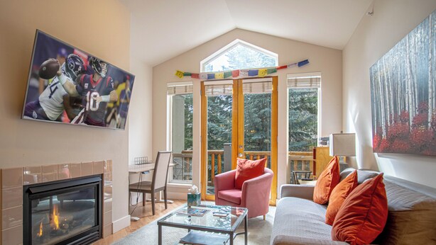 Ein Wohnzimmer mit Kamin, einer Couch, einem Couchtisch und einem Gemälde von einem Fußballspiel.