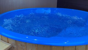 Een hottub met een houten buitenkant, tegen een houten wand.