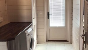 Een wasserette met een wasmachine, een droger en een deur naar een gang.