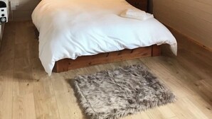 Een knus slaapkamer met een houten bed, een zacht vloerkleed en een hanglamp.