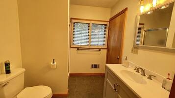 Ein Badezimmer mit Toilette, Waschbecken, Waschtisch und einem Fenster mit Jalousien.