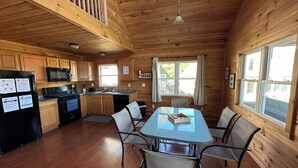 A wooden cabin with a kitchen, dining area, and large windows. - Heron Lodge - The Lodges at Oak Point, 1000 Islands - Right on the River! (Hammond)