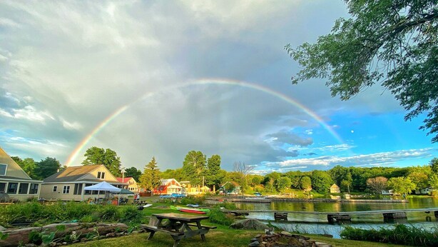 A lakeside scene with a picnic table, a canoe, and a rainbow. - Heron Lodge - The Lodges at Oak Point, 1000 Islands - Right on the River! (Hammond)