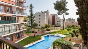 Un immeuble résidentiel doté d’une piscine, de balcons et d’un espace jardin.