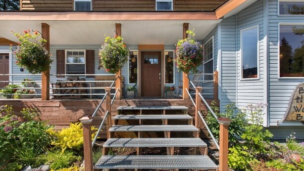 A wooden house with a porch, a staircase, and hanging flower baskets. - Mt.Benson Suite at Bell In the Woods B&B (King/Queen/2xTwin/Bottom Flr) Max6ppl (Seward)
