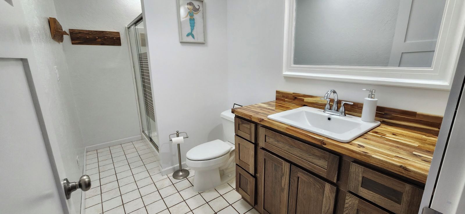 A small bathroom with a white toilet, a sink with a wooden countertop, and a mirror above the sink.