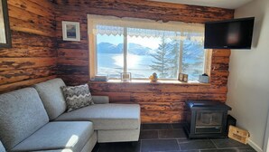 Um quarto aconchegante com sofá, lareira, televisão e janela com vista para as montanhas.