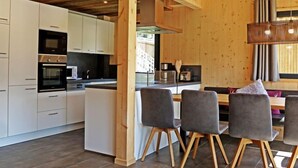 A modern kitchen with white cabinets, built-in appliances, and a wooden ceiling.
