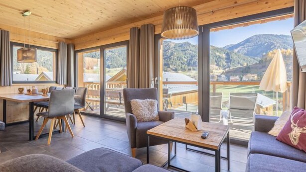 A modern interior with a dining area, seating, and large windows offering mountain views.