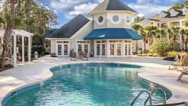 Une grande maison dotée d’une piscine, d’un belvédère et d’une terrasse couverte.