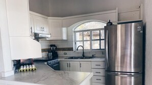A kitchen with white cabinets, a stainless steel refrigerator, and a window above the sink. - Casa Vika, Now with WIFI (Barras de Piaxtla)