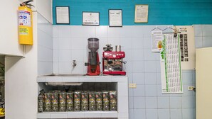 A kitchen with a coffee machine, a fire extinguisher, and coffee bags on shelves. - Hotel Ayenda Los Tres Pinos (Bogotá)