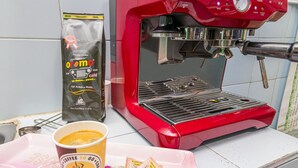 A coffee machine, a coffee cup, and a bag of coffee on a counter. - Hotel Ayenda Los Tres Pinos (Bogotá)