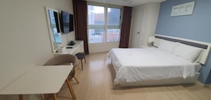 A hotel room with a bed, a desk, a chair, a television, and a window. - Hotel BELLIA (Busan)