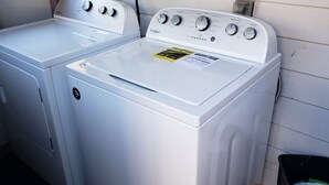 Uma lavanderia com duas máquinas de lavar e secar Whirlpool brancas.