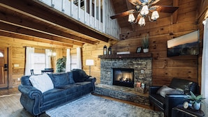 A cozy log cabin interior with a fireplace, leather sofas, and a wooden ceiling. - Bear Cavern *Minutes to Main Pigeon Forge Pkwy* (Pigeon Forge)