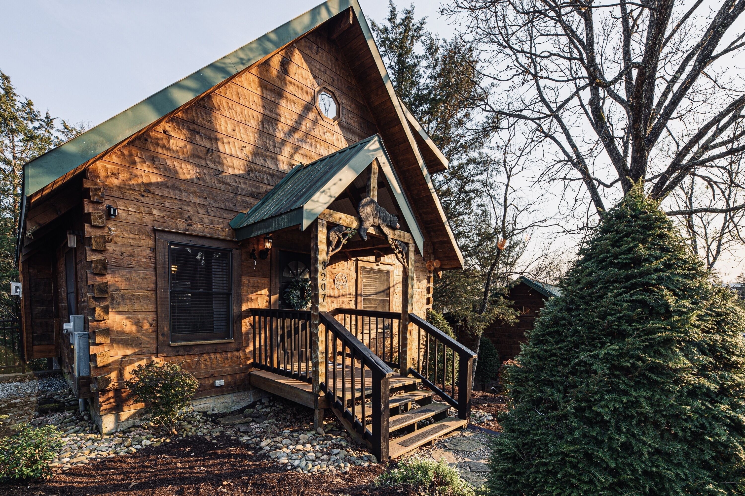 A rustic log cabin with a wooden exterior, a front porch, and a staircase leading to the entrance.