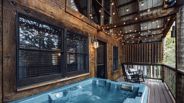 A wooden deck with a hot tub, large windows, and string lights. - Bear Cavern *Minutes to Main Pigeon Forge Pkwy* (Pigeon Forge)
