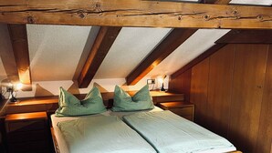 Une chambre à coucher avec un lit en bois, deux tables de chevet et un plafond en pente avec des poutres en bois.