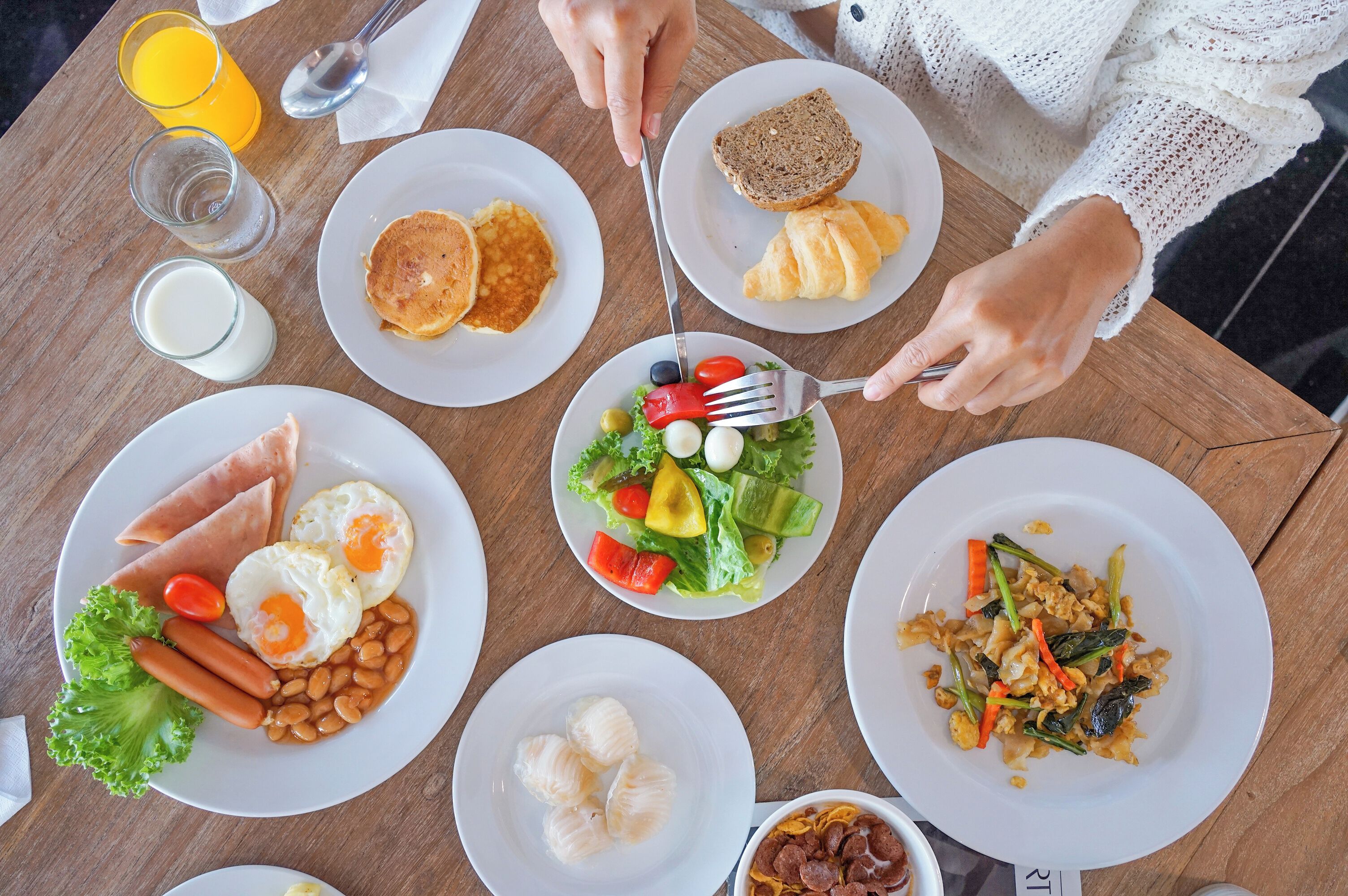 A table with various breakfast dishes including pancakes, eggs, toast, and vegetables.