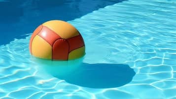 A single yellow and orange ball floating in a clear blue pool.