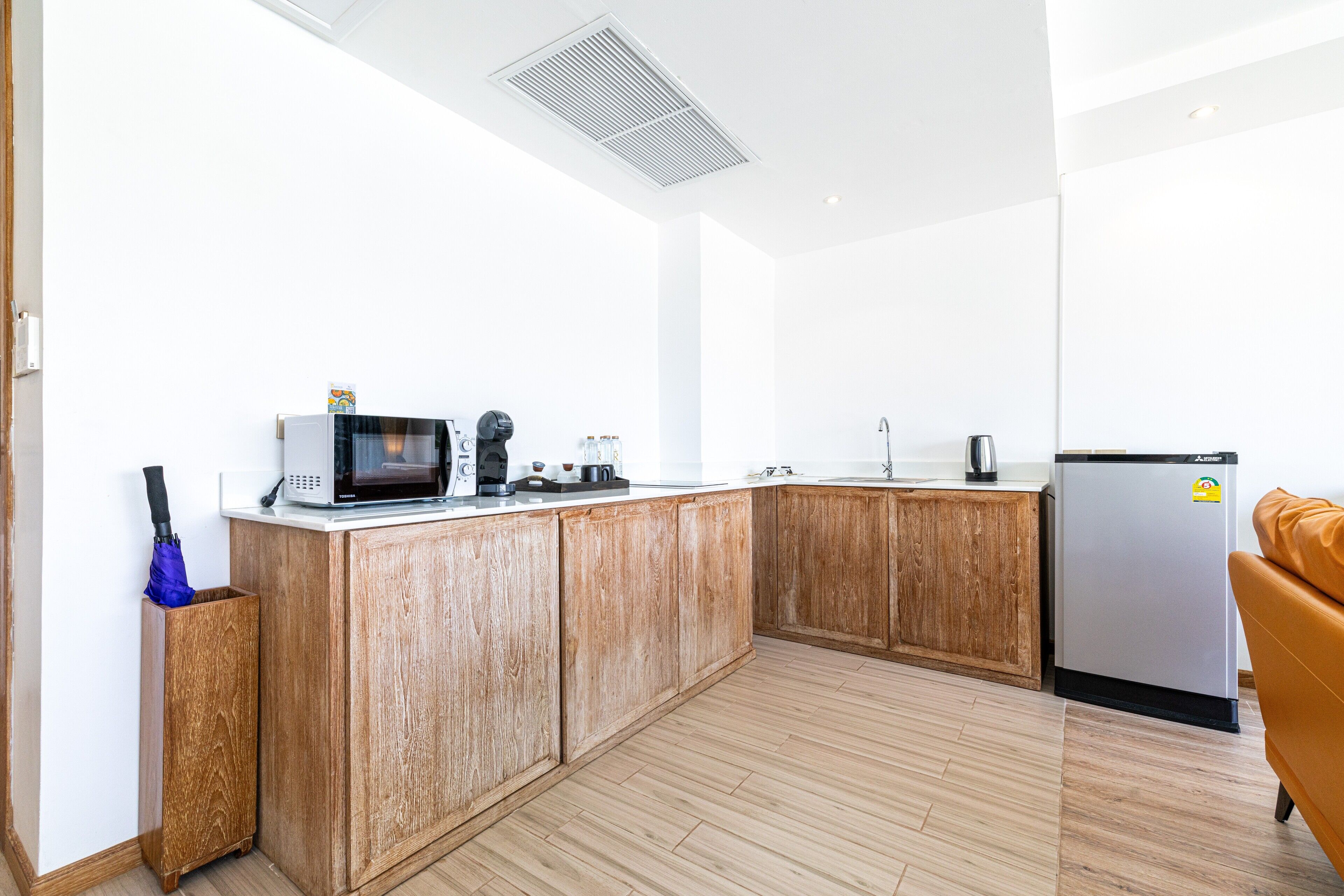 Una cocina moderna con armarios de madera, microondas, cafetera y refrigerador.
