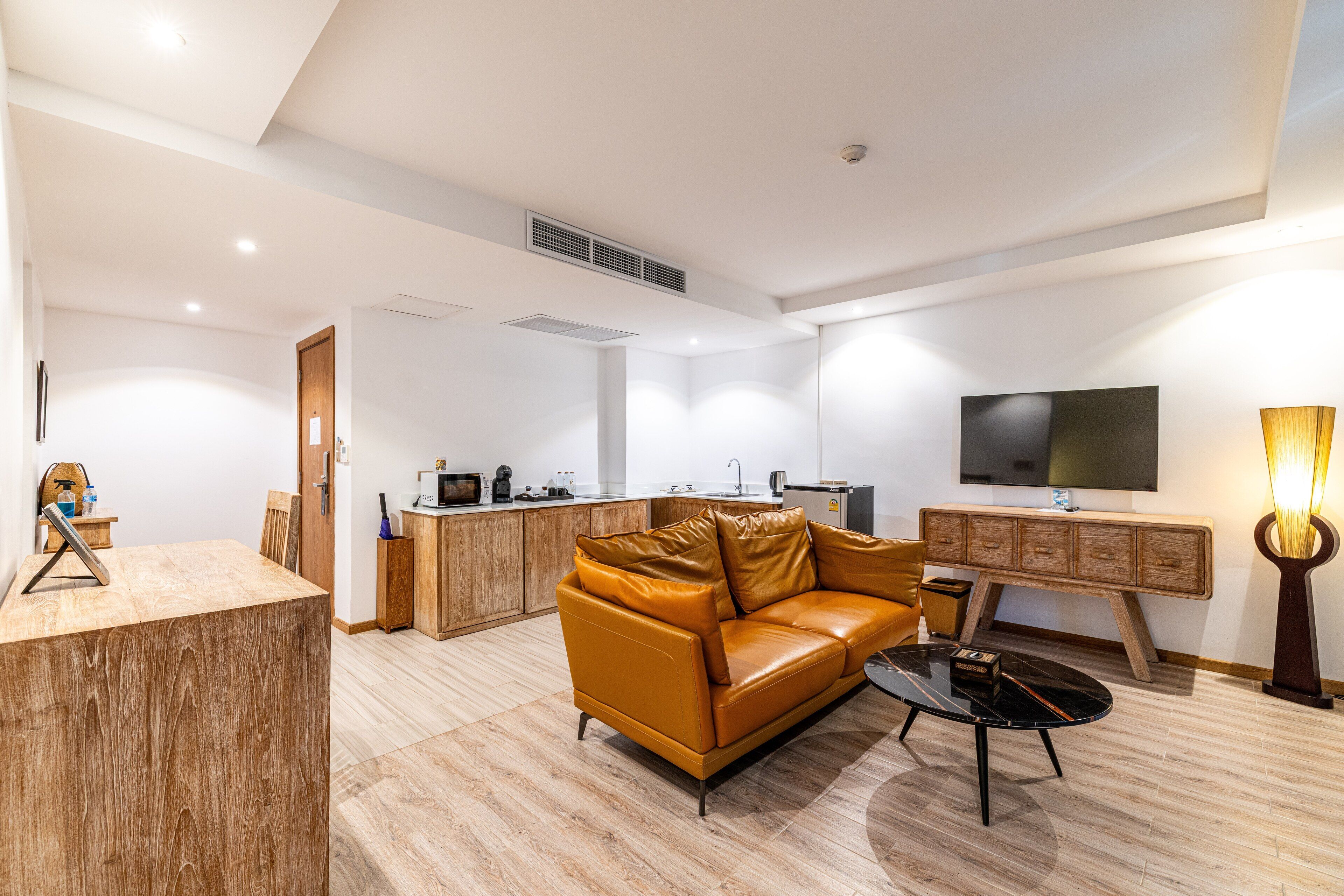 Una sala de estar moderna con un sofá de cuero, una mesa de centro, un televisor montado en la pared y un mueble de madera.